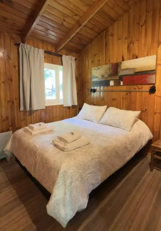 Un dormitorio con una cama grande, ropa de cama blanca y una ventana con cortinas.