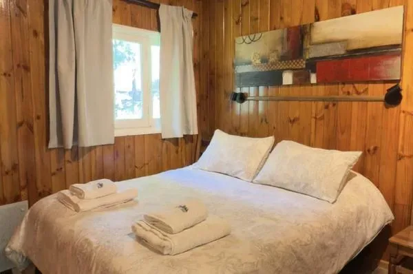 Un dormitorio con una cama, toallas dobladas y paredes revestidas de madera.