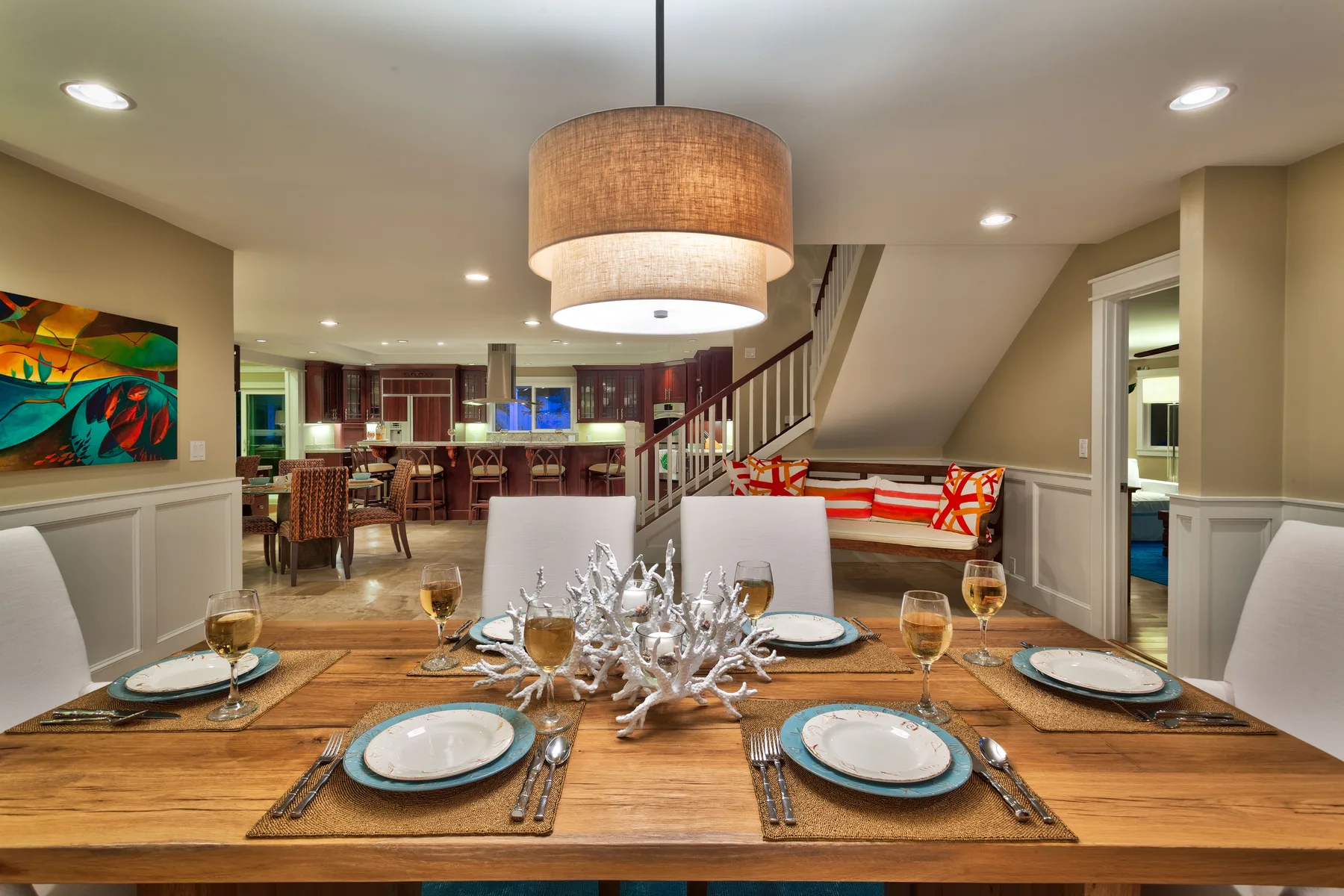 Dining area with a set table and an open kitchen beyond.