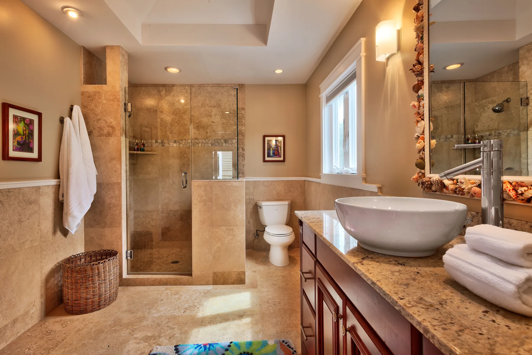 A bathroom with a glass shower, toilet, and vanity with a vessel sink.