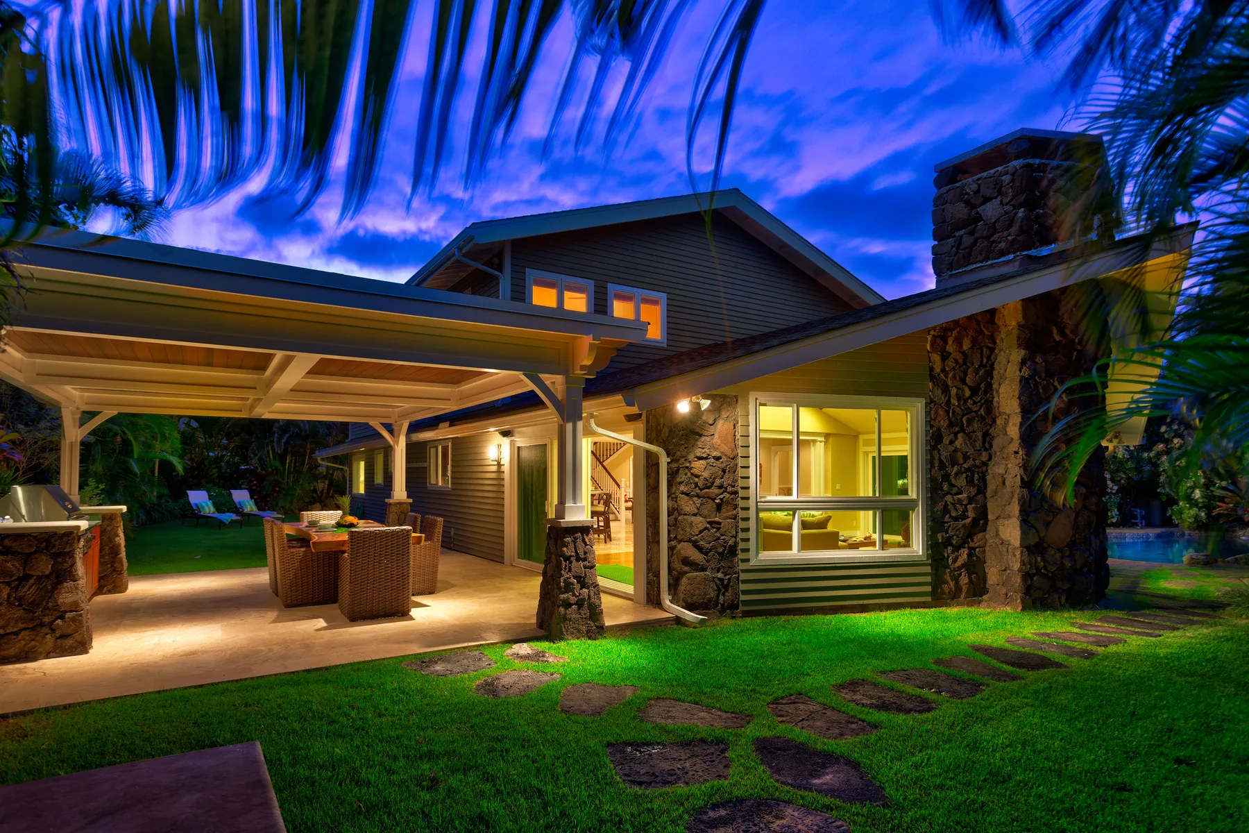 A house exterior at dusk, with a covered patio and illuminated windows.