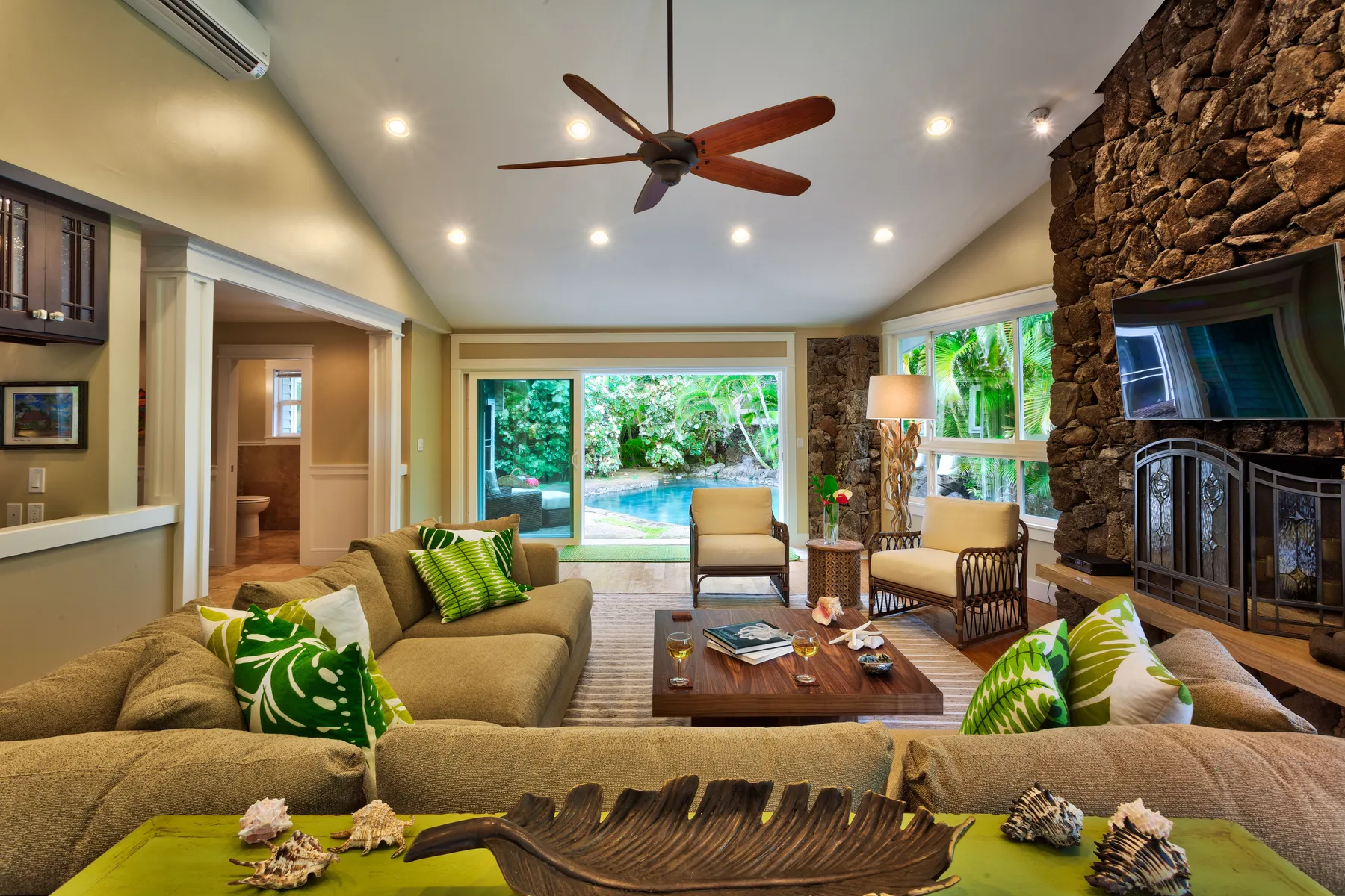 A living room with seating around a coffee table and a stone fireplace.