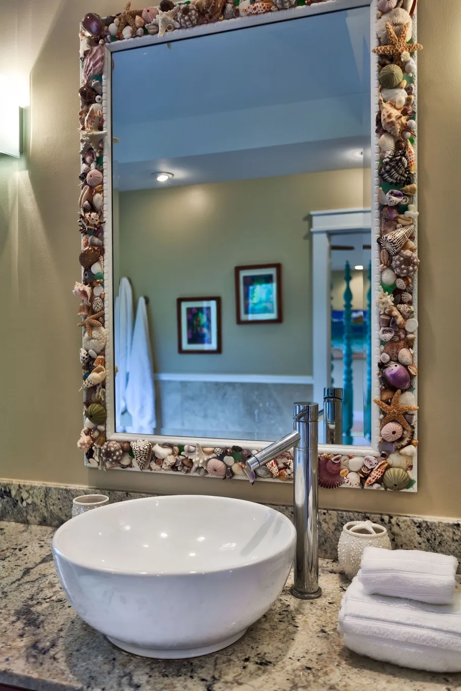 A bathroom vanity with a vessel sink and a large shell-framed mirror.