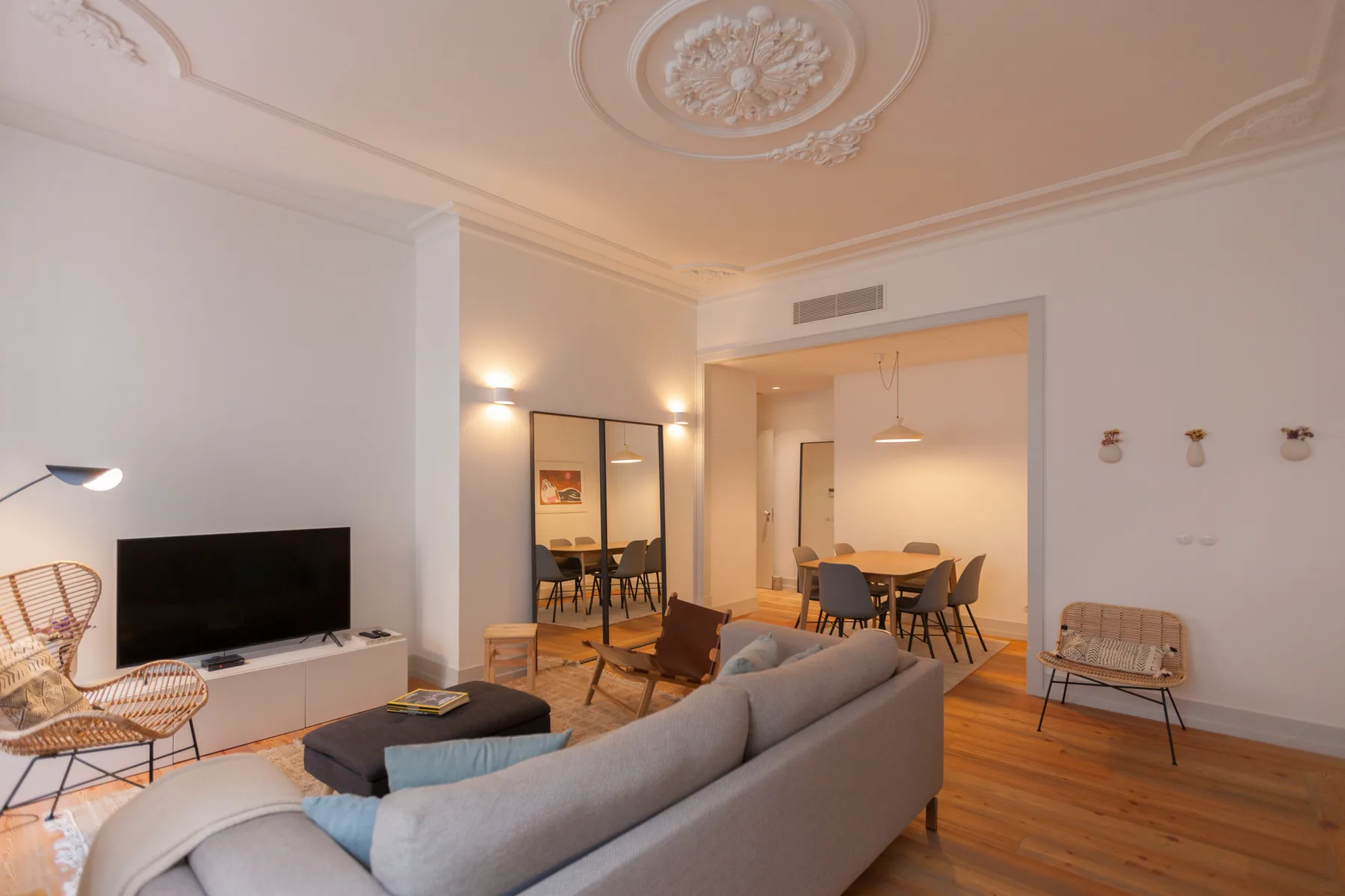 Una sala de estar y comedor con sofá, televisor y mesa de comedor.