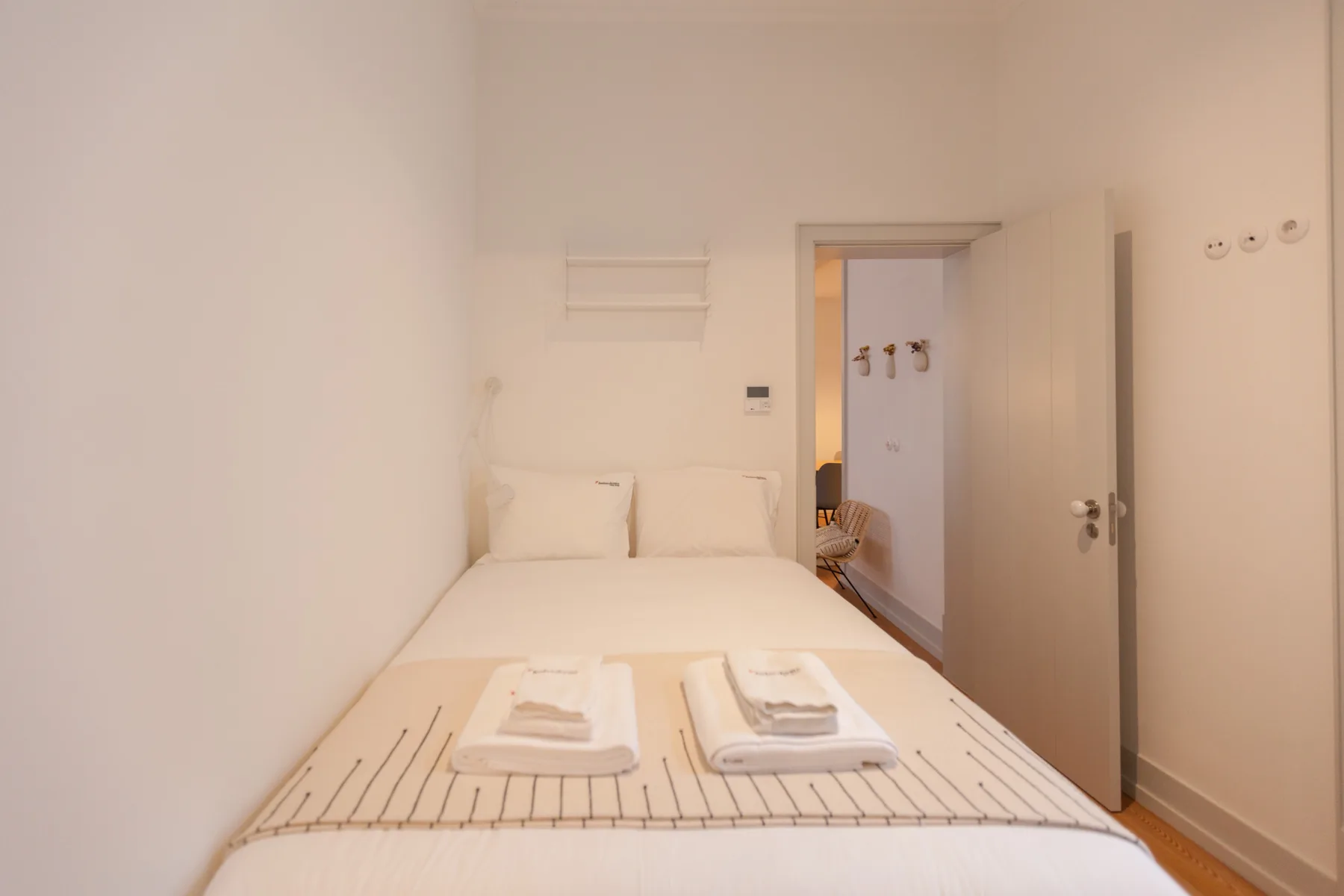 Un dormitorio con una cama bien hecha y una puerta abierta.