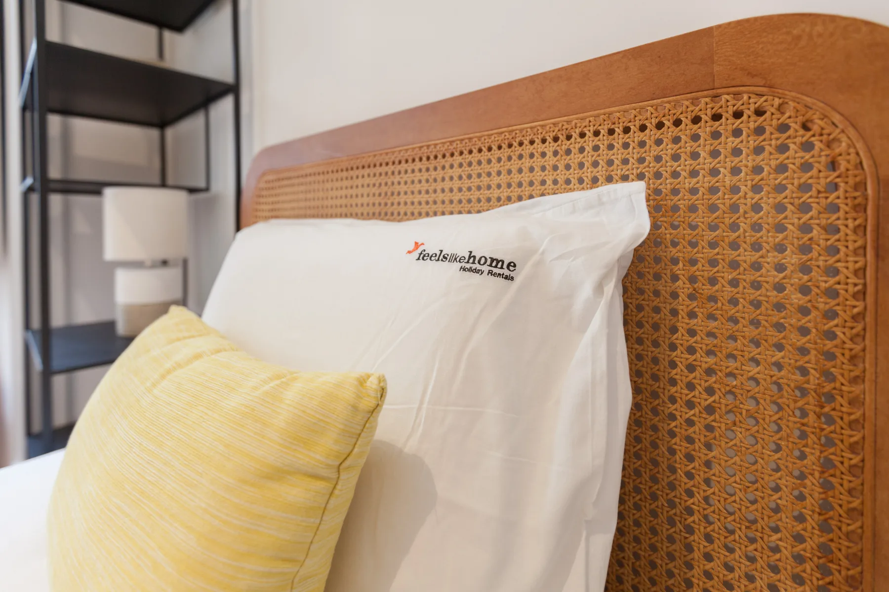 Una zona de dormitorio con almohadas apoyadas contra un cabecero tejido.