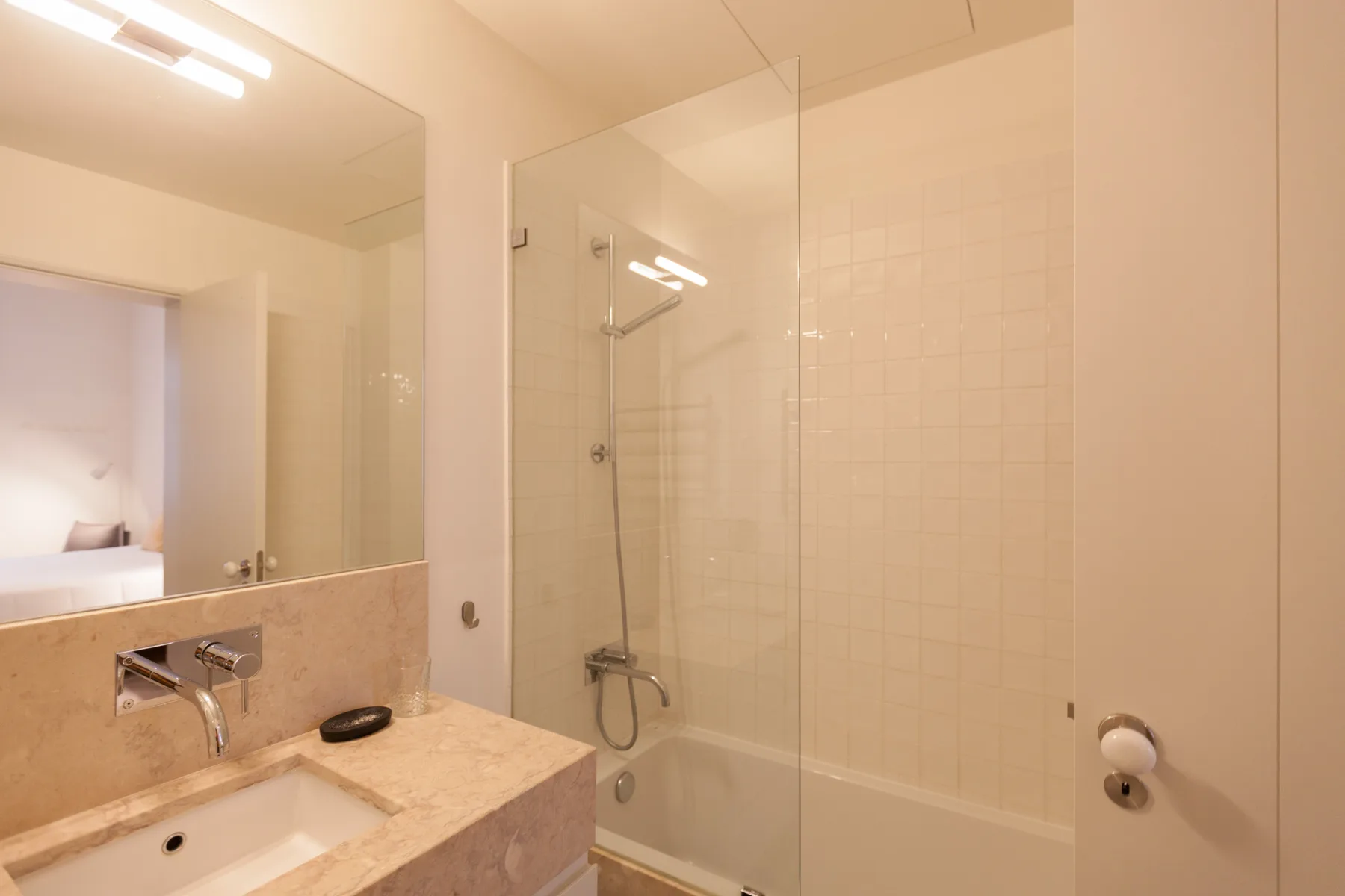 Un baño con lavabo y ducha con mampara de vidrio.