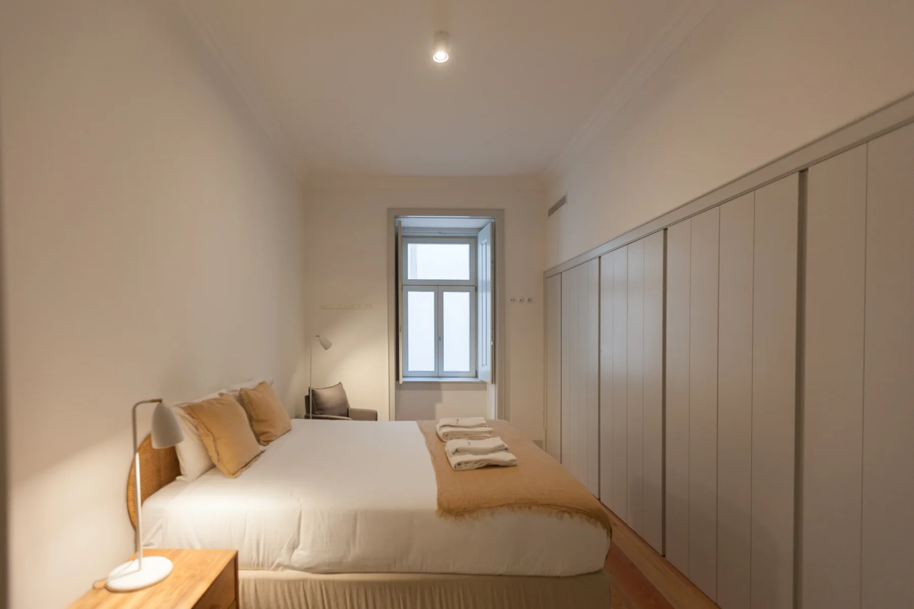 Un dormitorio con una cama bien arreglada y armarios empotrados.