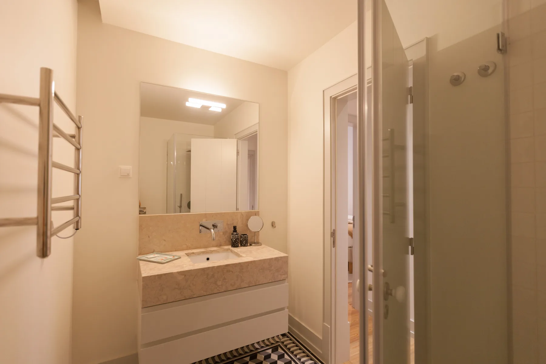 Un baño con un amplio lavabo, espejo y mampara de ducha de vidrio.