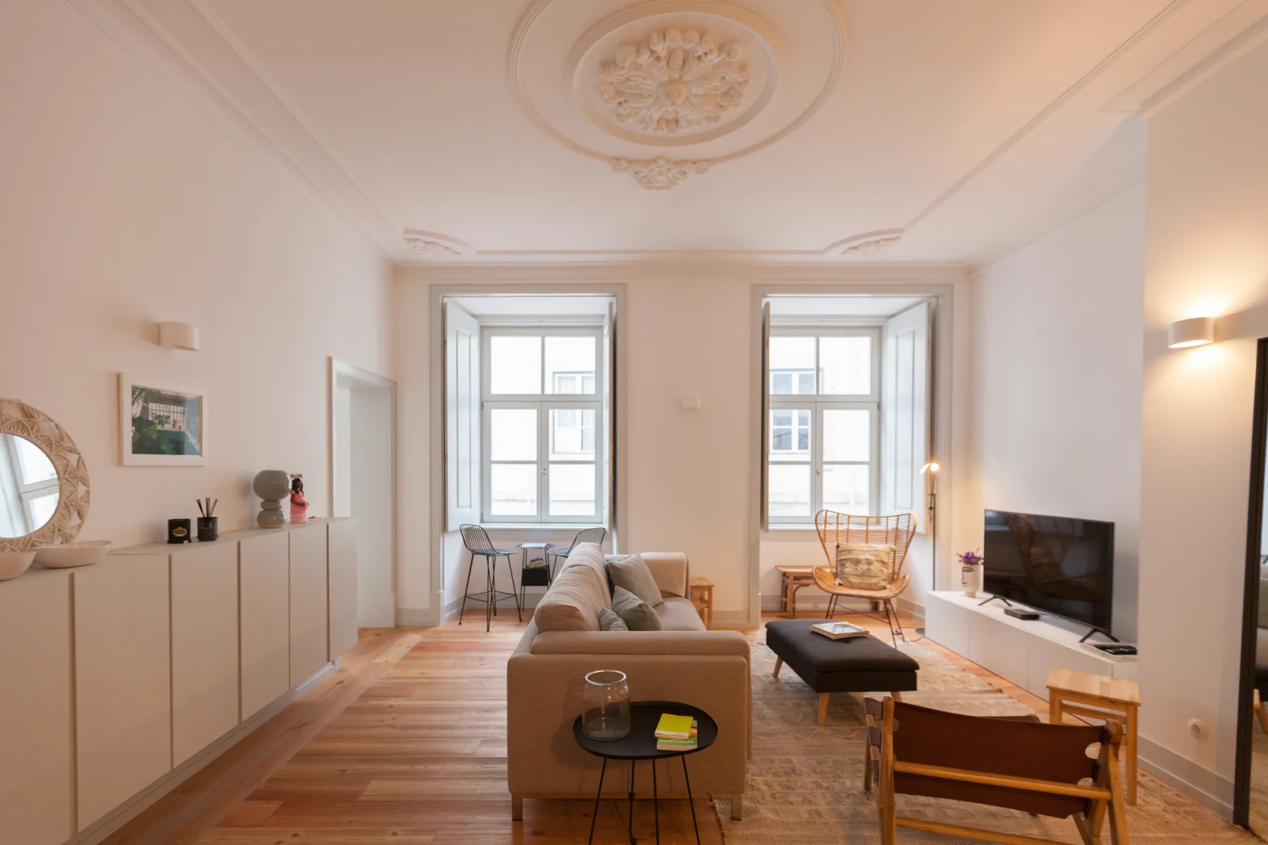 Una sala luminosa con asientos, un televisor y ventanas altas.