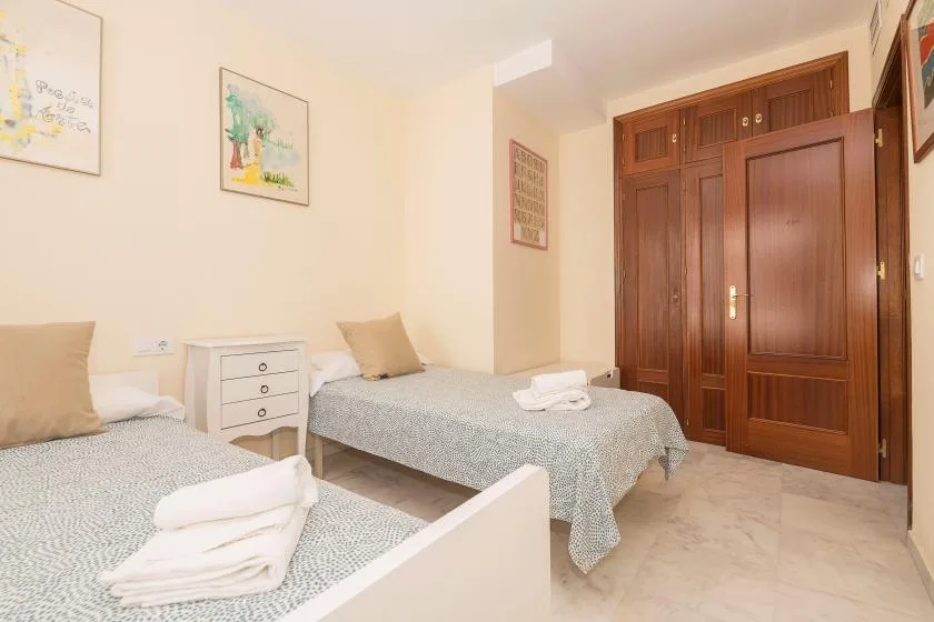 Un dormitorio con dos camas, una mesita de noche y armarios de madera.