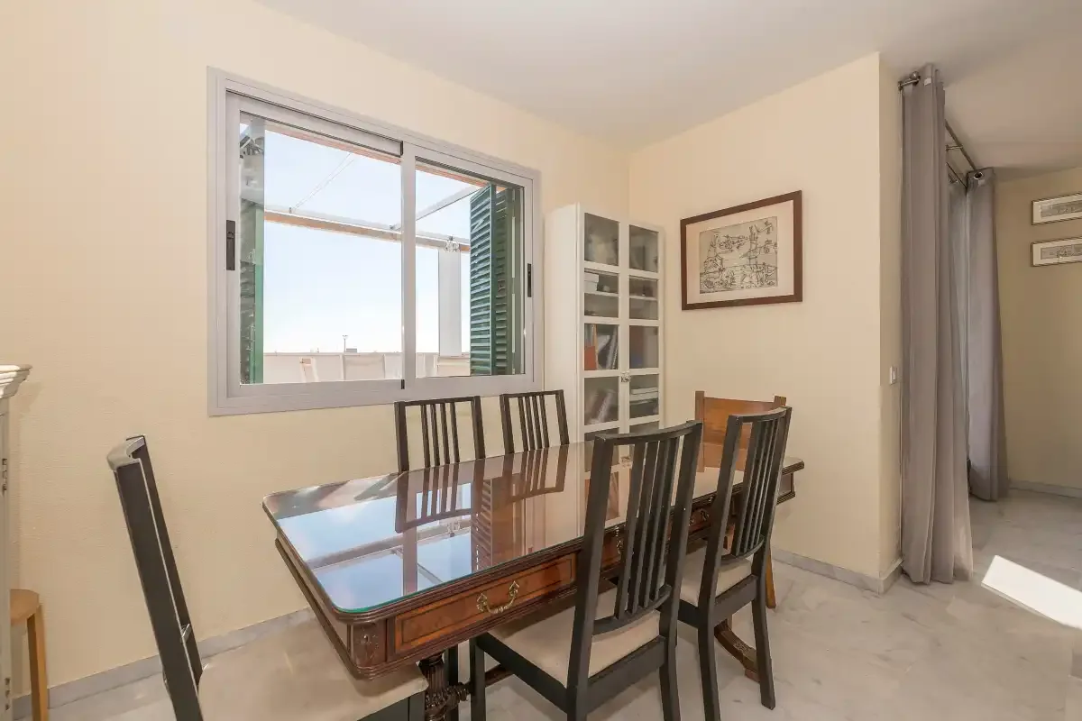 Comedor con una mesa rectangular y sillas junto a una ventana.