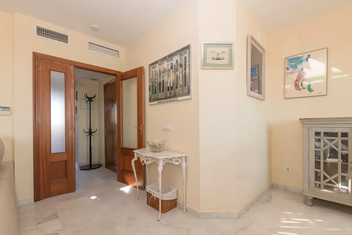 Un pasillo interior con puertas de madera y cuadros en las paredes.
