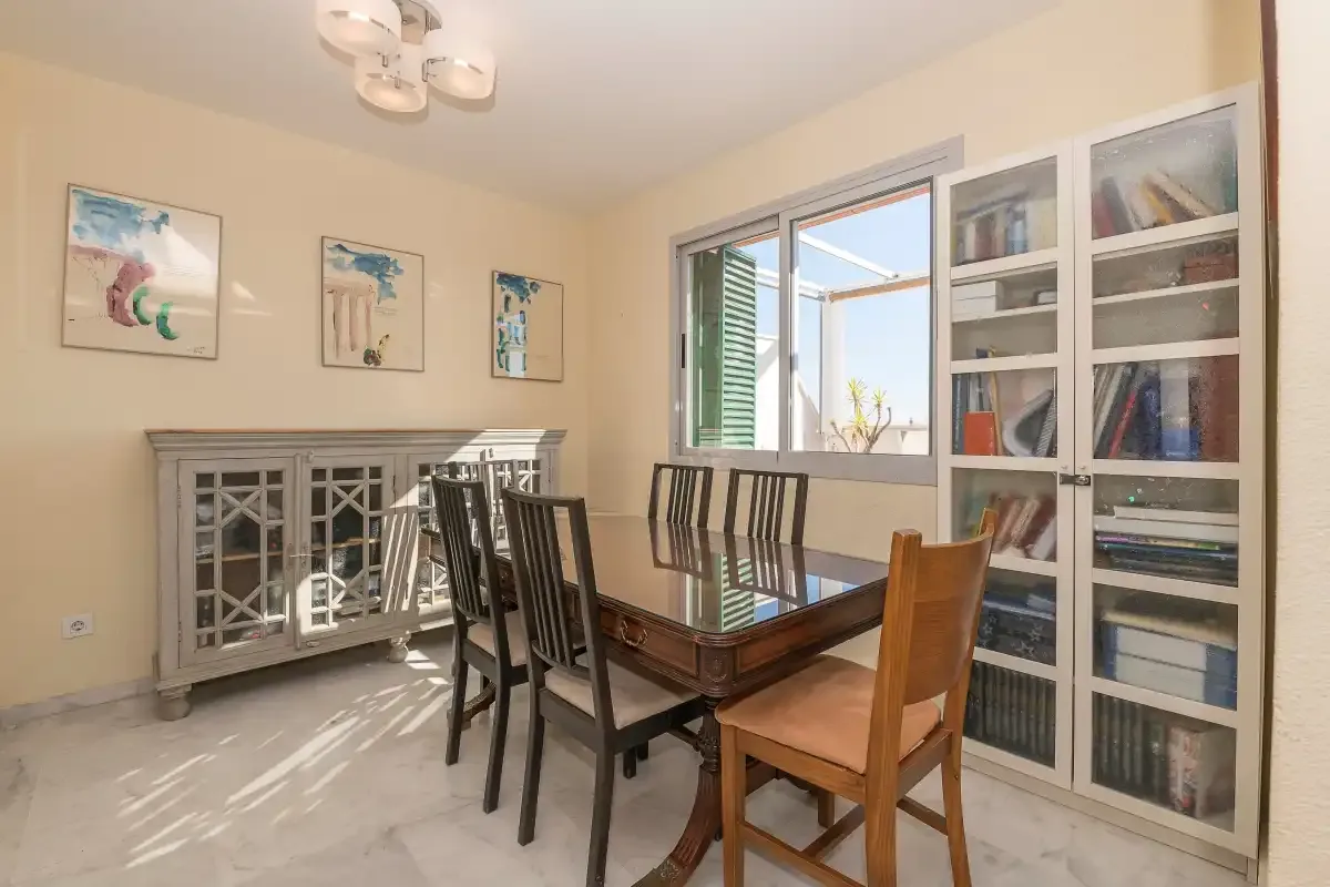 Comedor con una mesa de madera, sillas y estanterías empotradas.