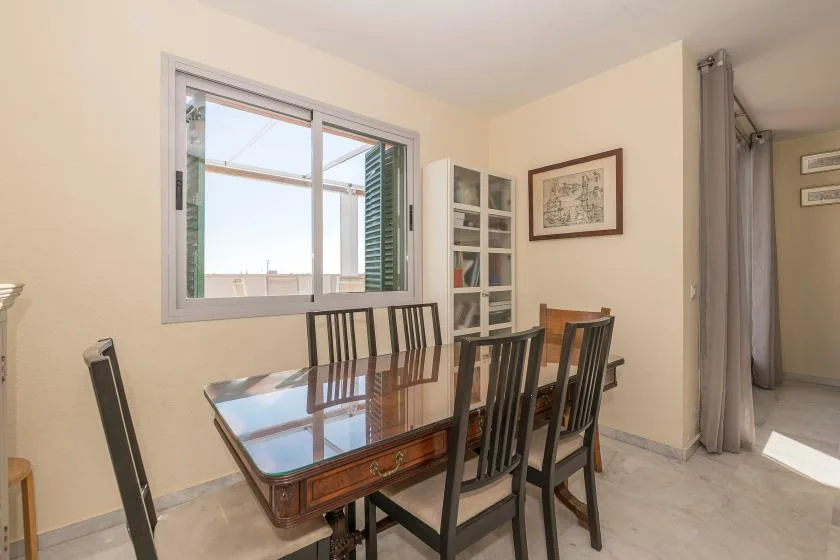 Un comedor con una mesa de madera y sillas junto a una ventana grande.
