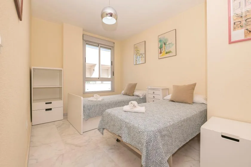 Un dormitorio con dos camas, una ventana y una mesita de noche.