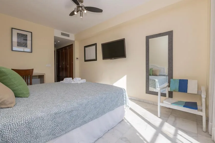 Un dormitorio con una cama grande, un televisor en la pared y un espejo de cuerpo entero.