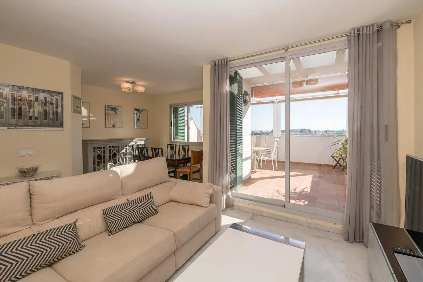 A bright living room opens onto a balcony through wide glass doors.