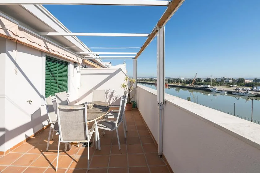A tiled rooftop terrace has outdoor seating beside a waterfront view.