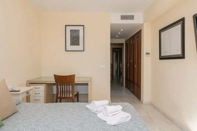 Un dormitorio con una cama, un escritorio y una silla junto a un pasillo.
