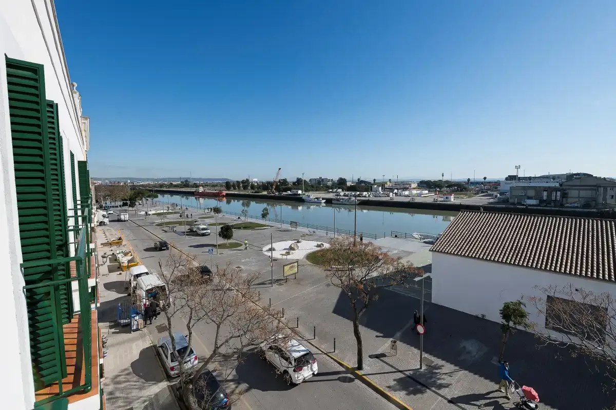 Una calle junto al agua y una zona de estacionamiento bordean un canal bajo un cielo despejado.