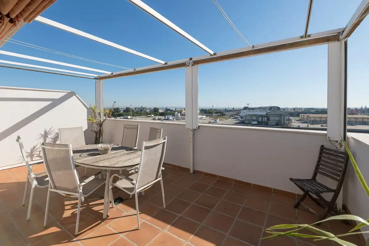 Una terraza amueblada con asientos bajo una pérgola blanca.