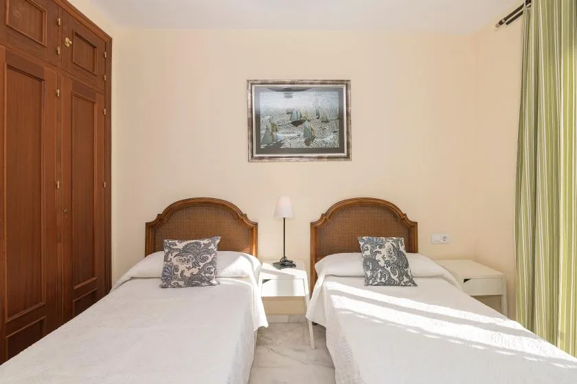 Un dormitorio con dos camas individuales, mesitas de noche y un cuadro en la pared.
