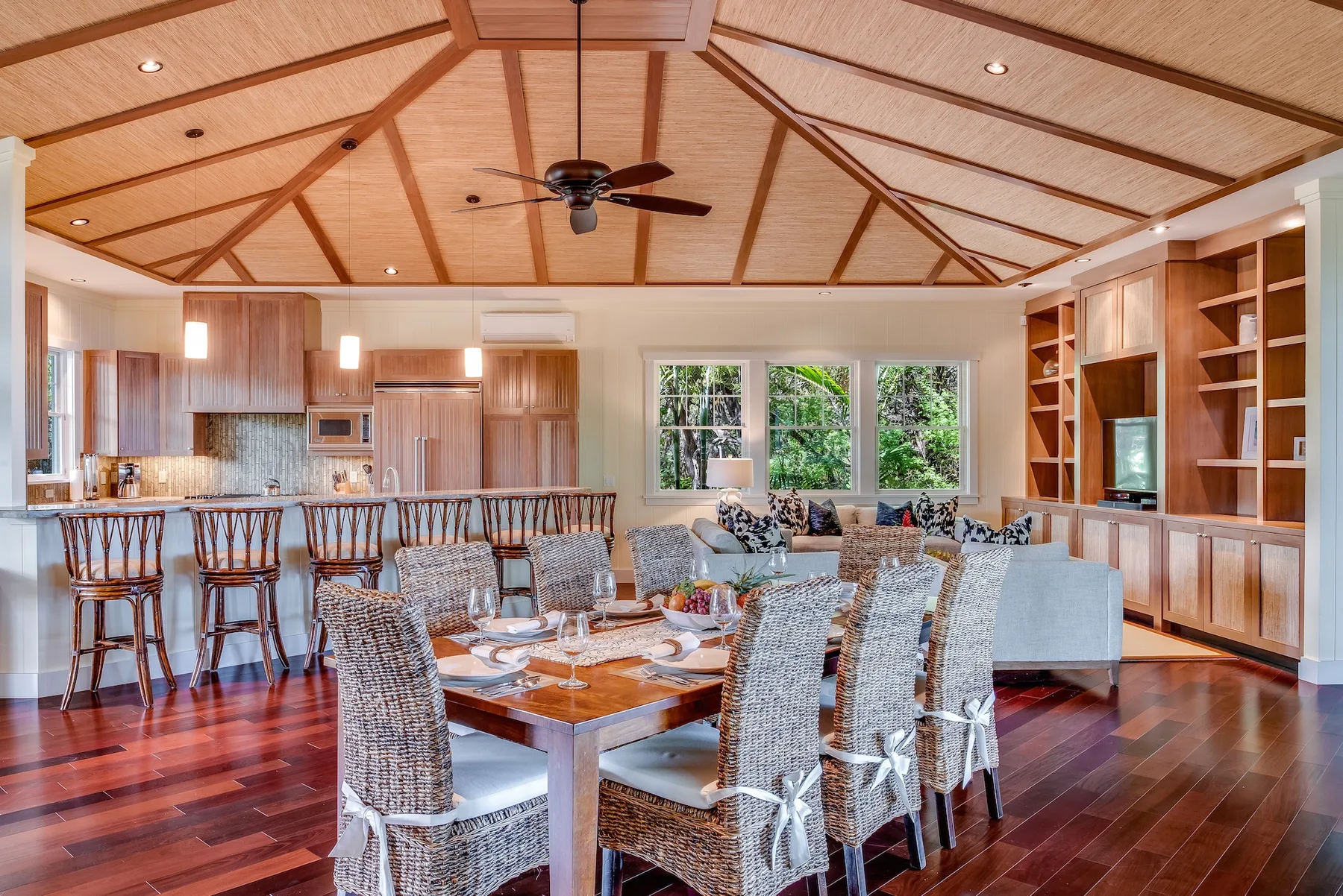 Un amplio comedor y cocina de concepto abierto, con una mesa de madera y asientos tejidos.