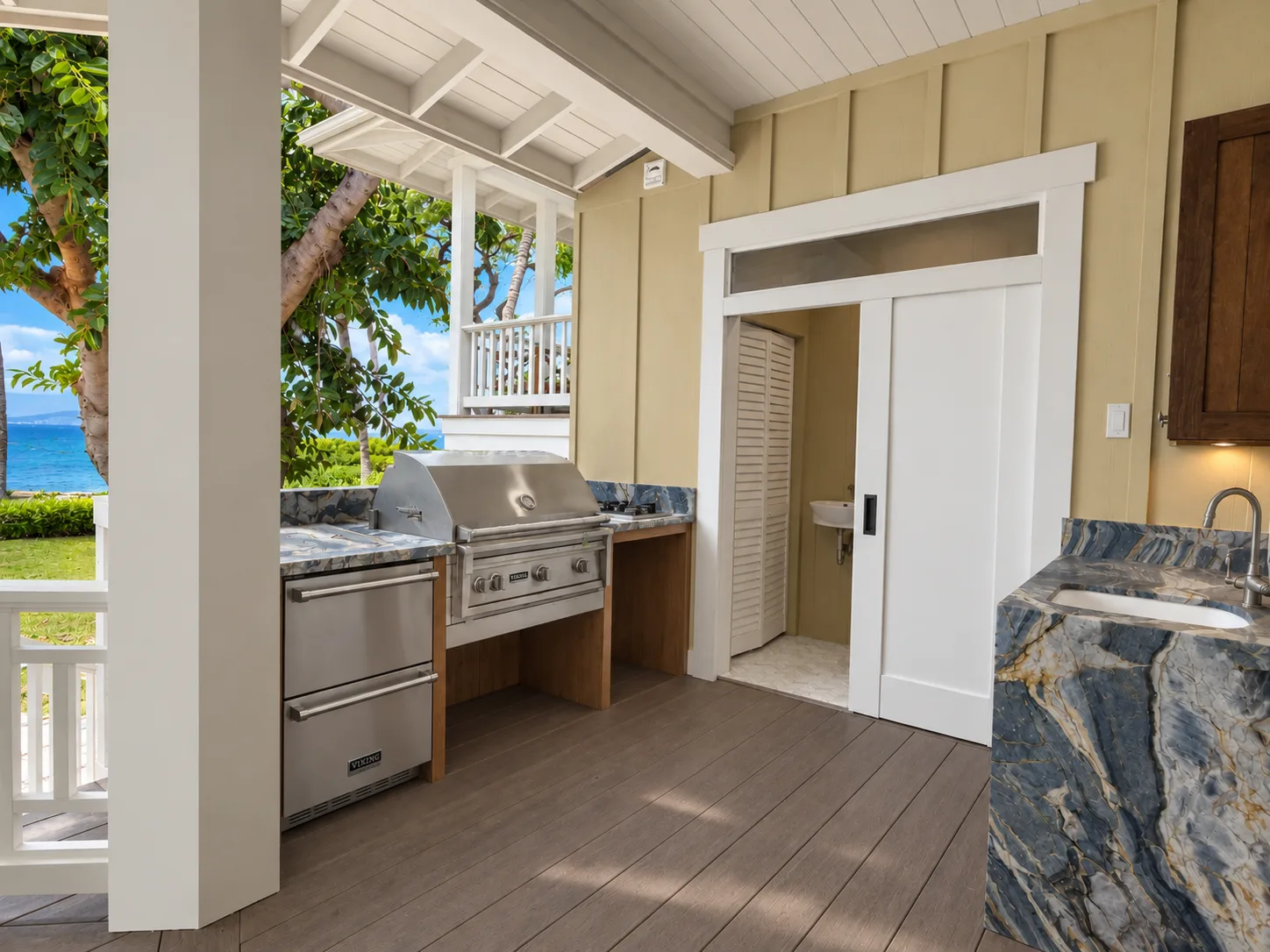 Una cocina exterior cubierta con parrilla, encimera y vista al mar.