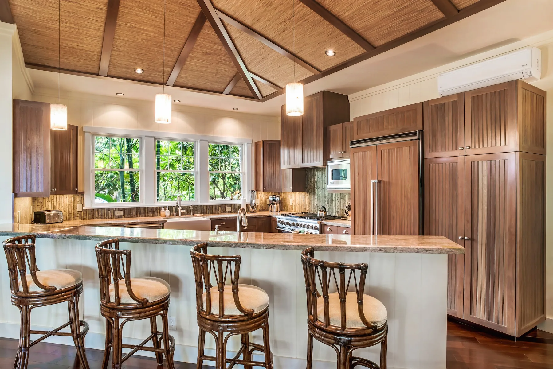 Una cocina amplia con isla central, gabinetes de madera y asientos de barra.