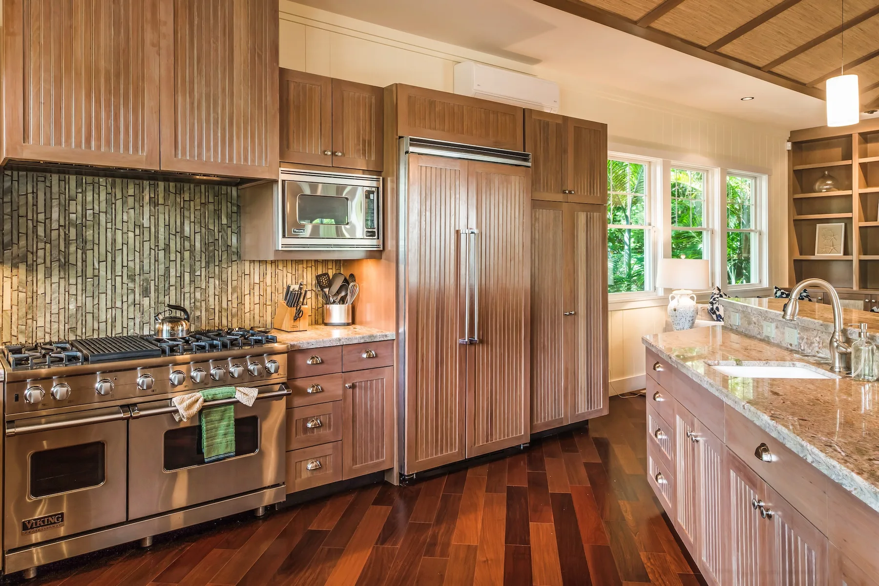 Una cocina amplia con gabinetes de madera, electrodomésticos de acero inoxidable y una isla central.