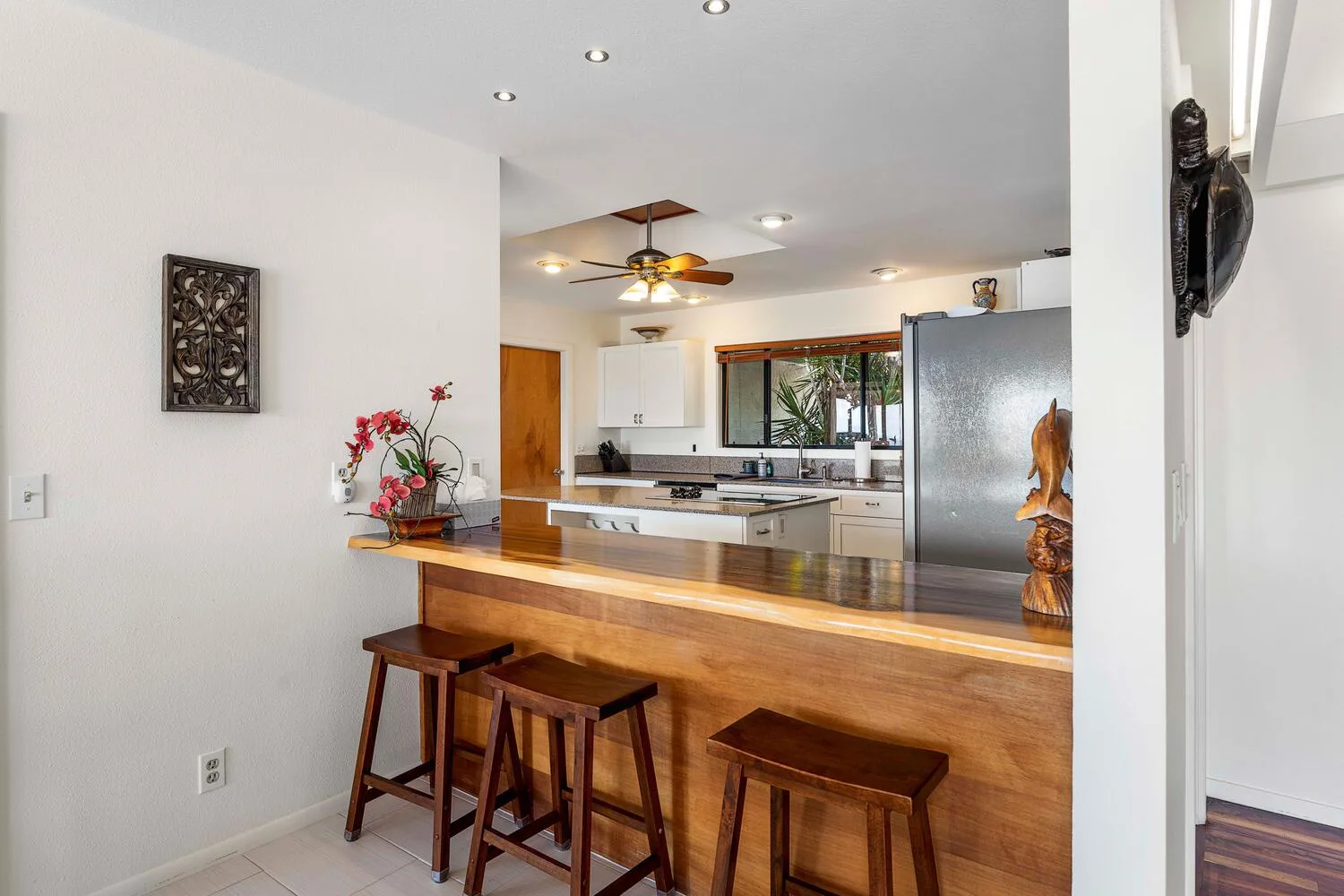 Una cocina abierta con una barra larga de madera y taburetes.