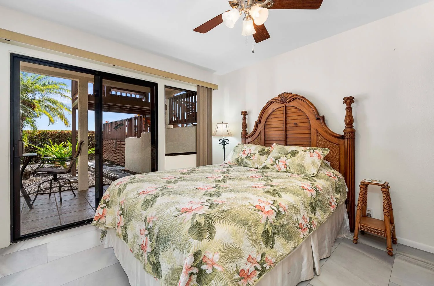 Un dormitorio con una cama cubierta con flores junto a puertas de vidrio que dan a un patio.