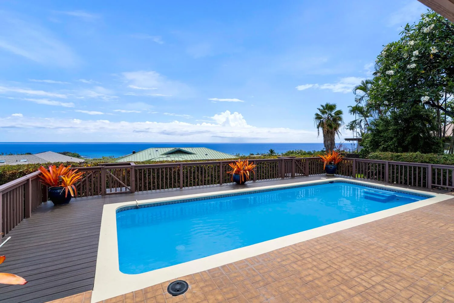 Una piscina al aire libre se encuentra en una terraza de madera con vista al mar.