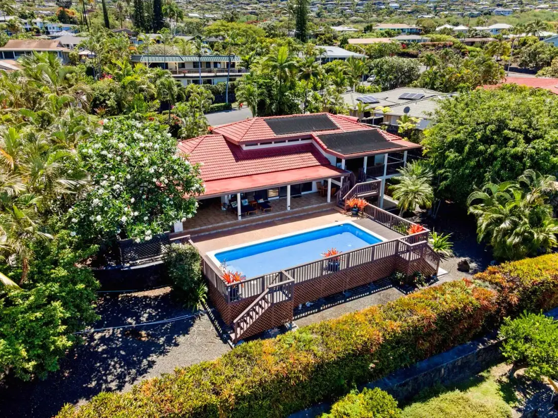 Una vista elevada muestra un edificio de techo rojo junto a una piscina azul.