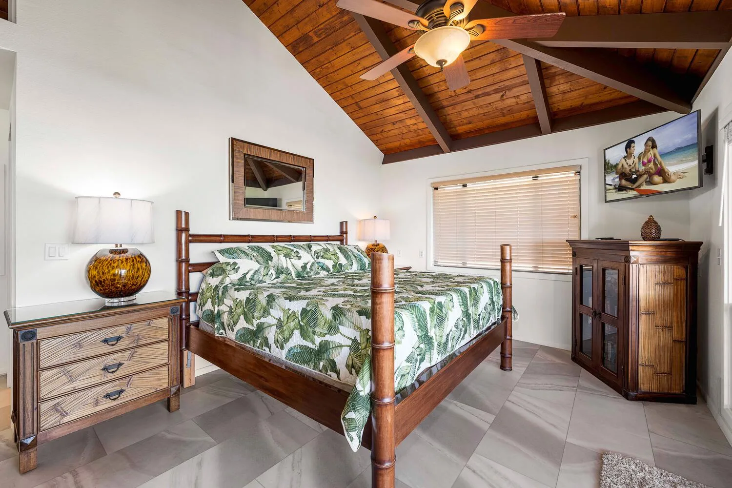 Un dormitorio con cama de madera, ropa de cama con hojas y techo inclinado de madera.