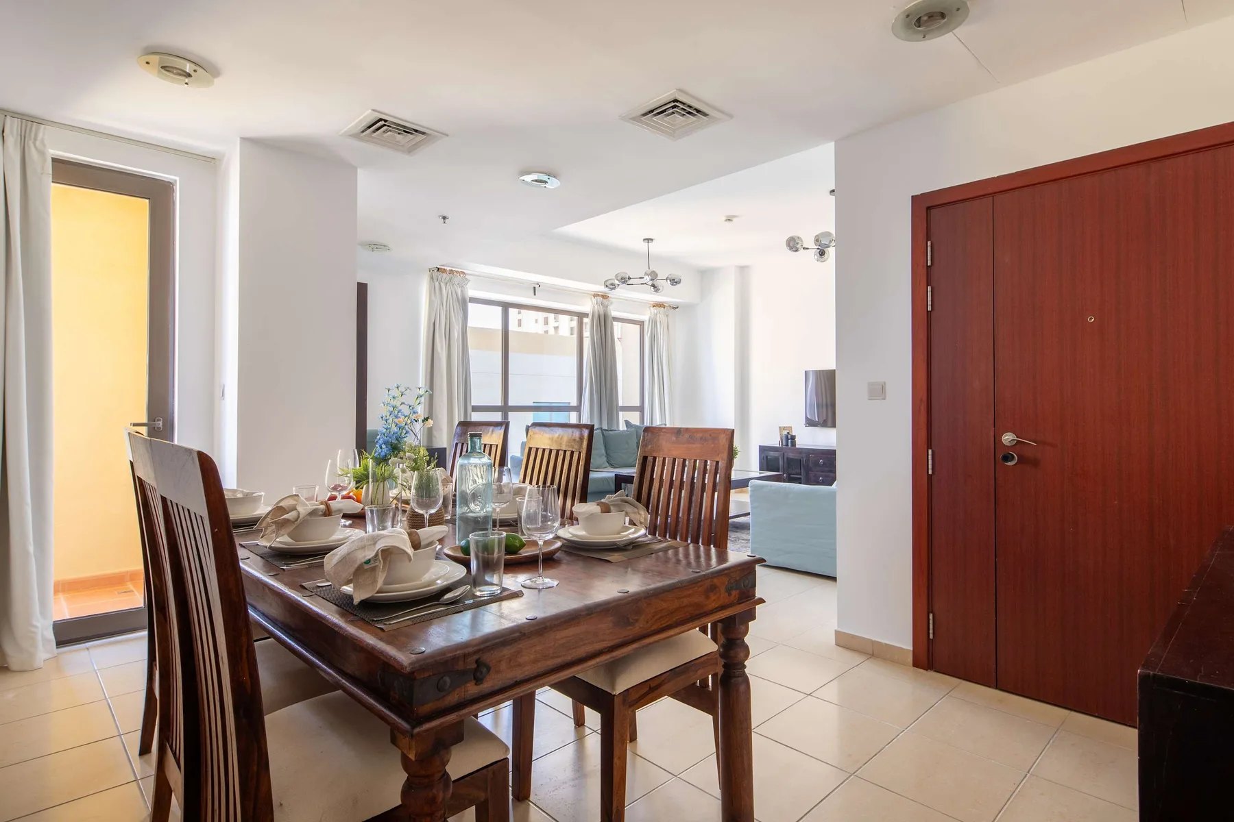 Comedor con la mesa puesta junto a una gran puerta de entrada de madera.