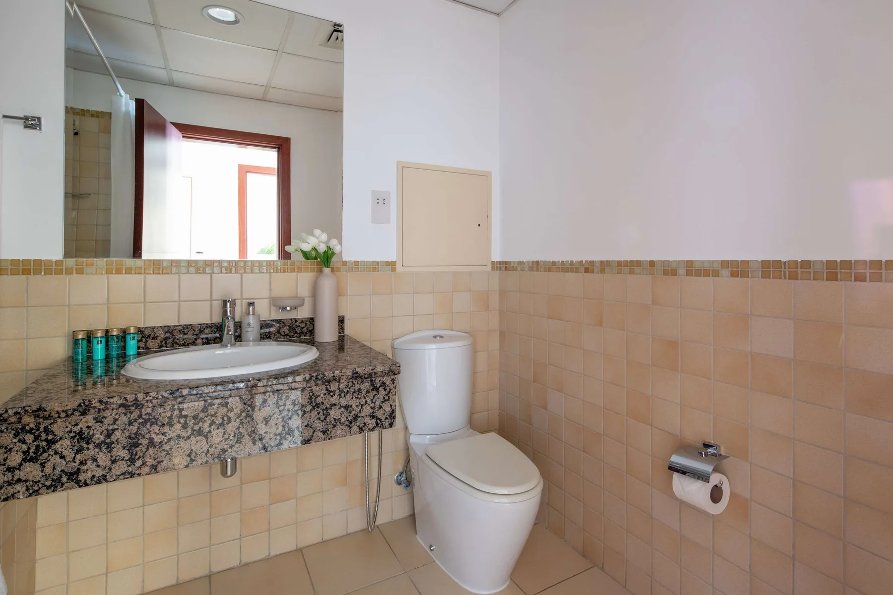 Un baño con azulejos, lavabo, espejo e inodoro.
