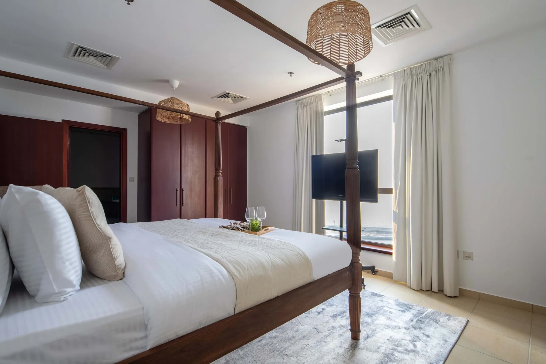 Un dormitorio con una cama con dosel y un televisor junto a la ventana.