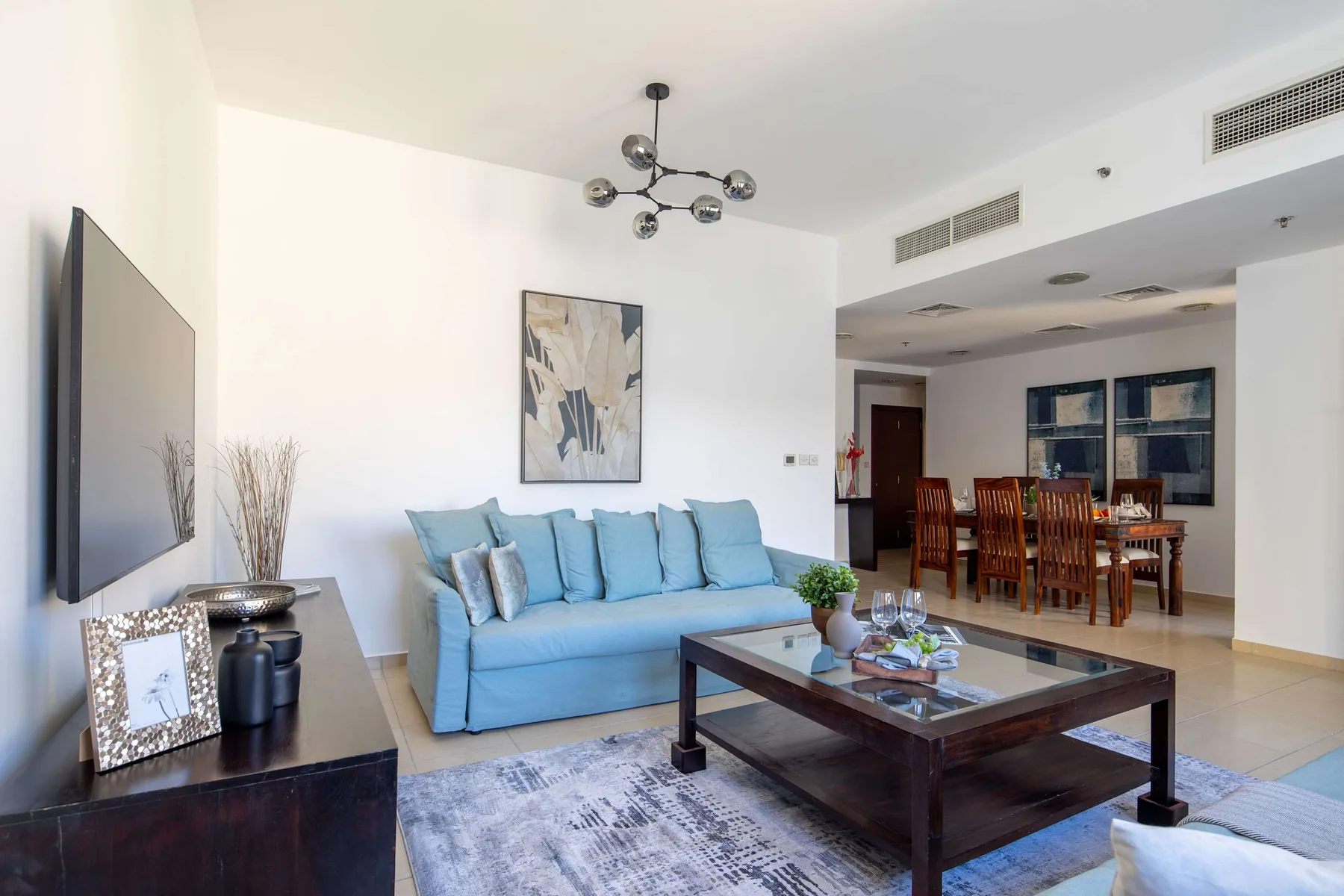 Una luminosa sala de estar y comedor con asientos azules y una mesa de comedor.
