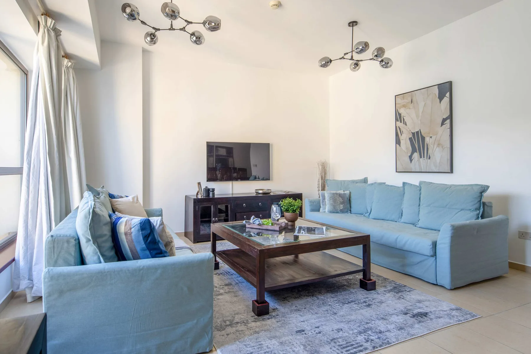 Una sala de estar luminosa con asientos azules y una mesa de centro de madera.