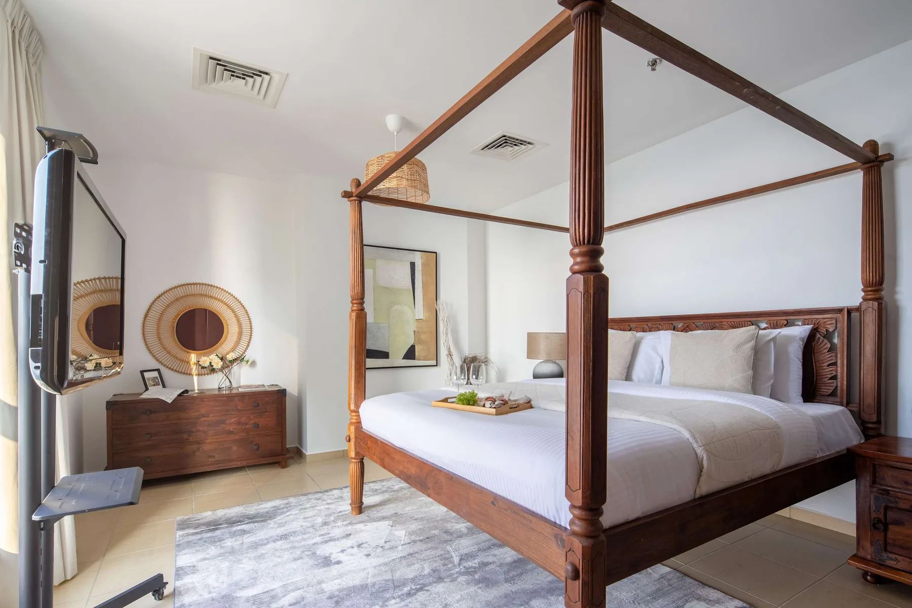 Un dormitorio con una cama con dosel de madera, ropa de cama blanca y una cómoda.