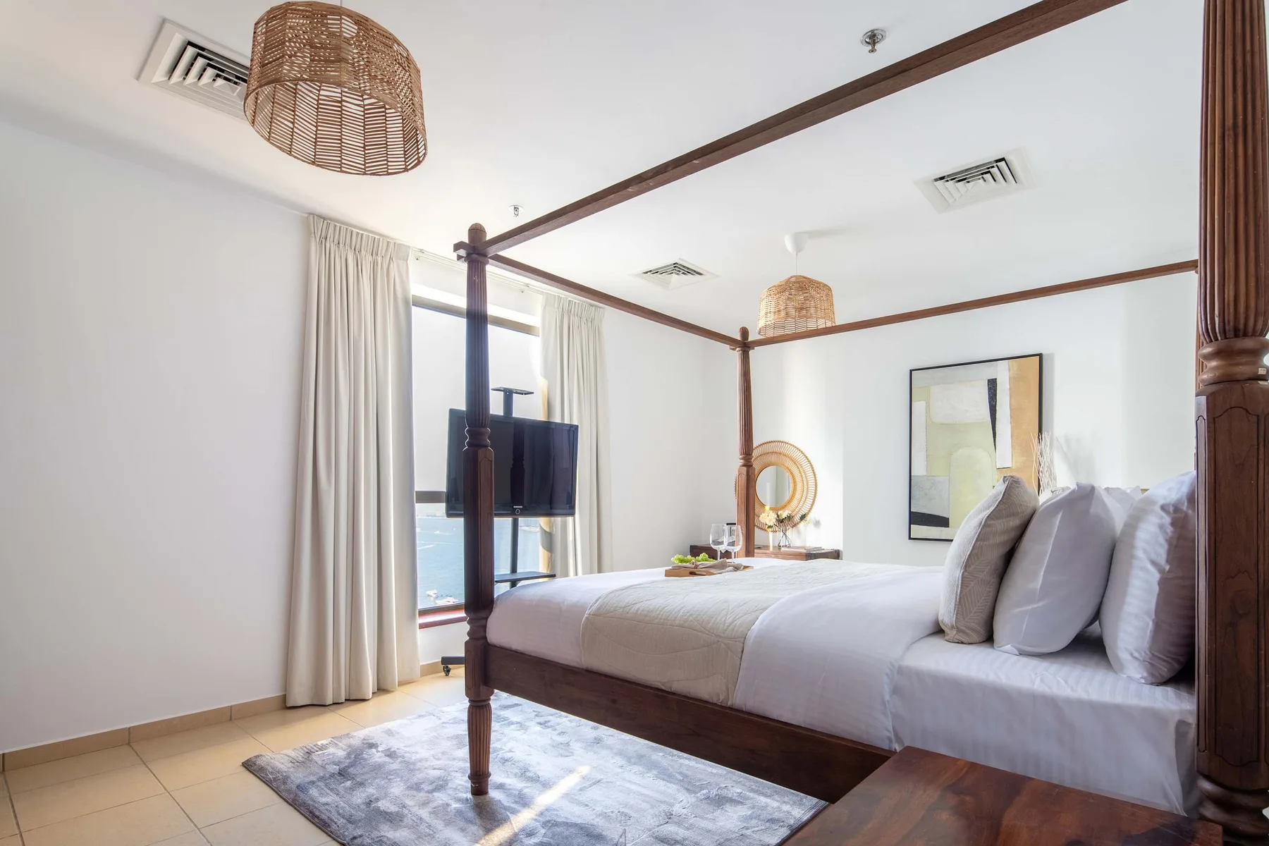 Un dormitorio luminoso con una cama con dosel y cortinas claras.