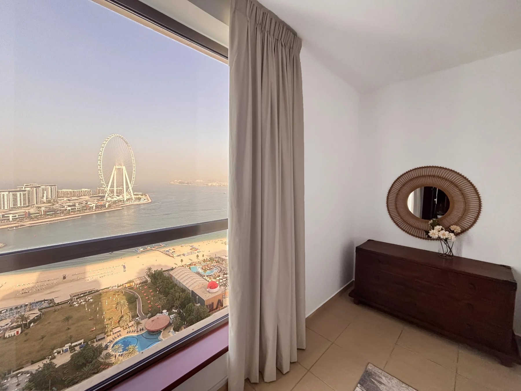 Una habitación con una gran ventana que da a la playa y al paseo marítimo.
