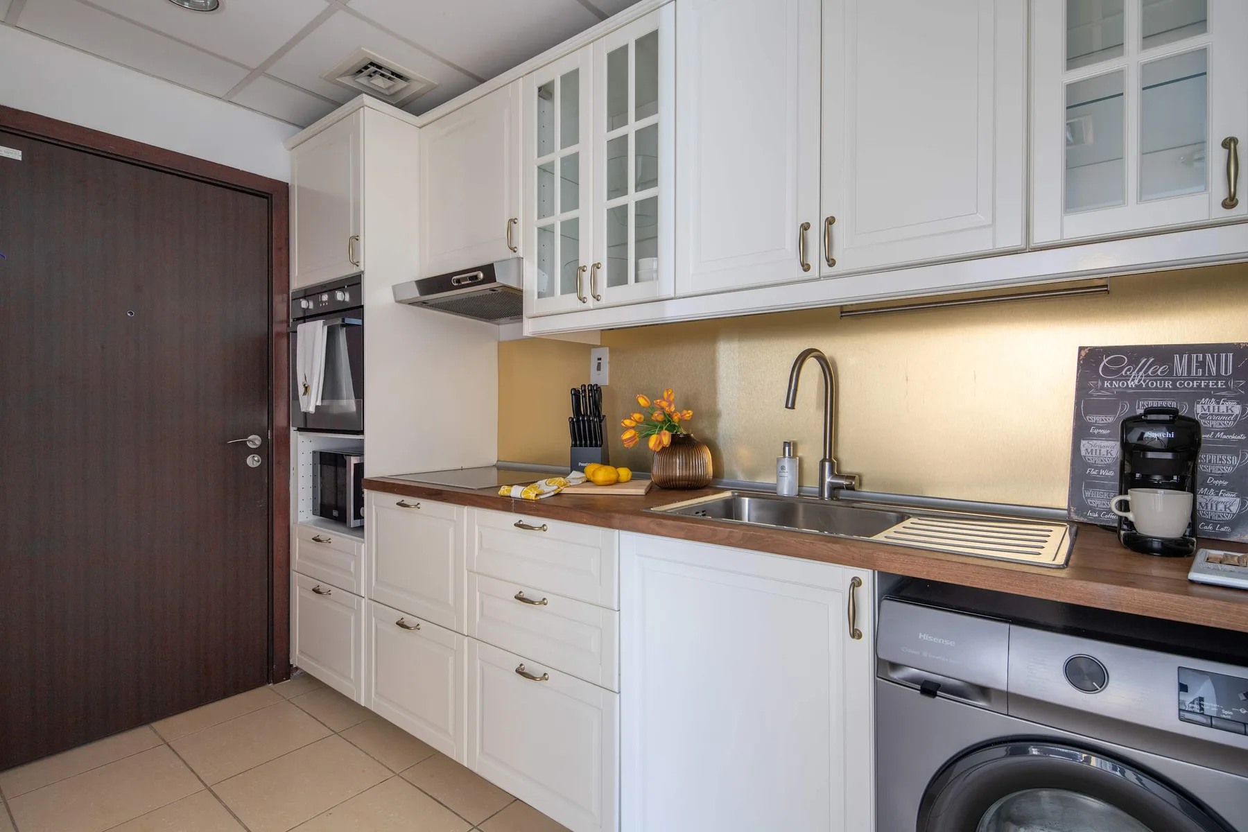 Una cocina luminosa con gabinetes blancos, una encimera y un fregadero.
