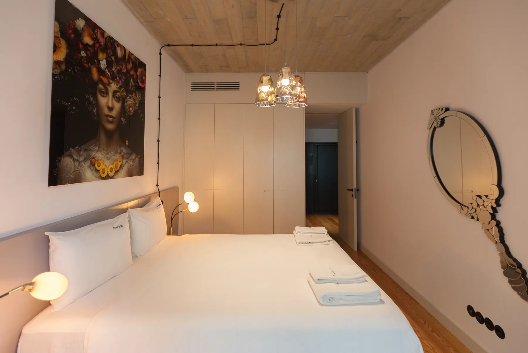 A bedroom with a neatly made bed and framed artwork on the wall.