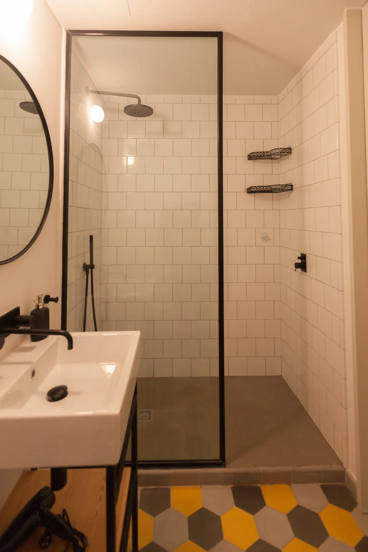 A tiled bathroom with a shower, sink, and colorful geometric floor tiles.