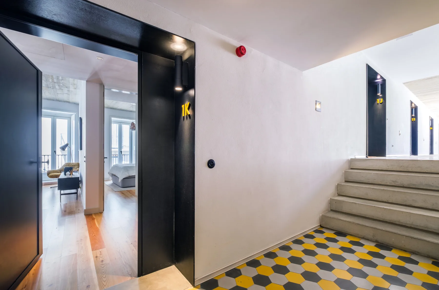 An interior hallway with dark doors, tiled flooring, and a short flight of stairs.