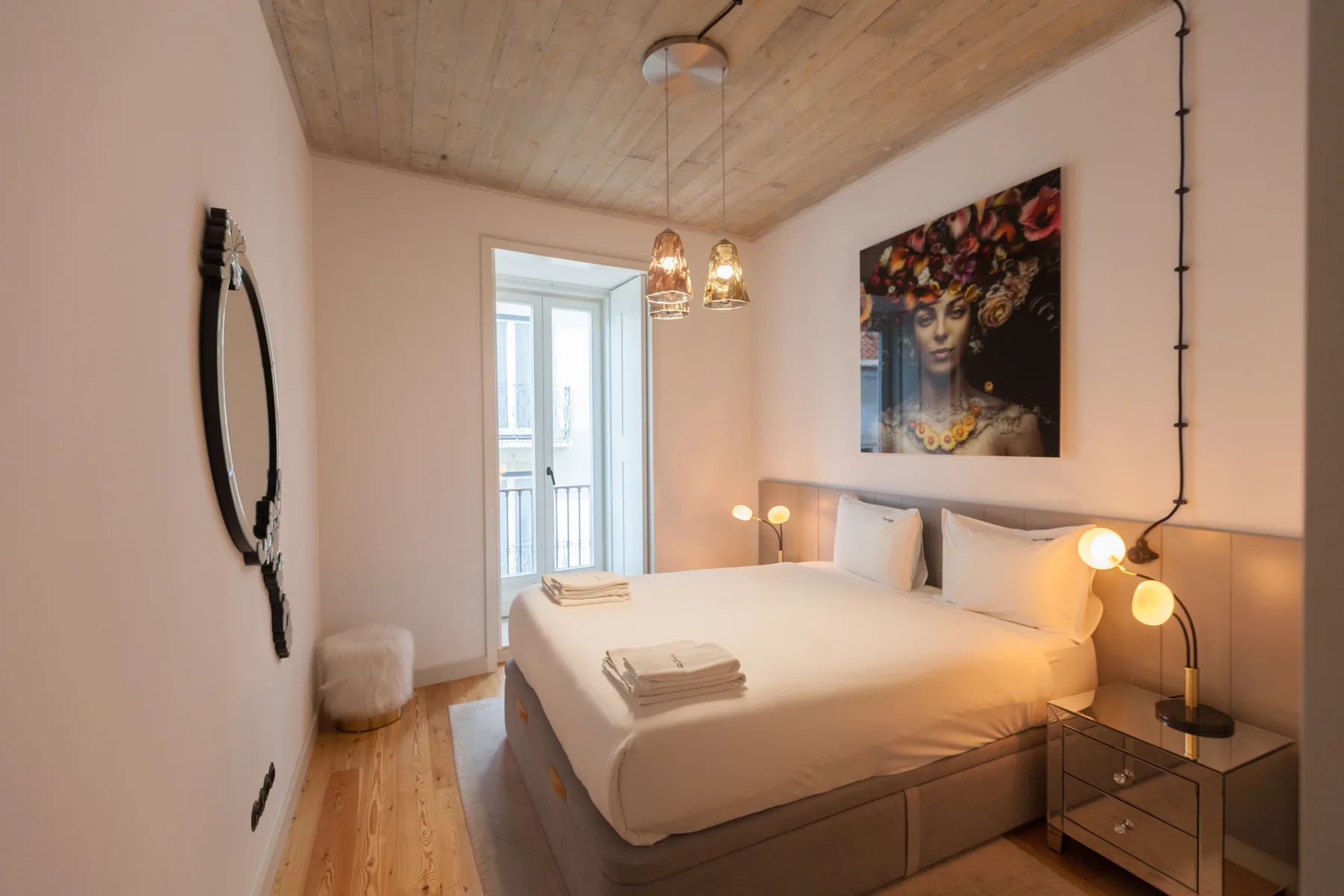 Un dormitorio con una cama doble, mesitas de noche y una obra grande sobre la cama.