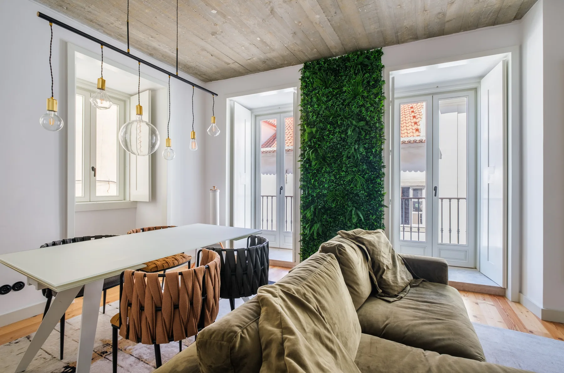 A bright living and dining area with seating, a table, and tall windows.